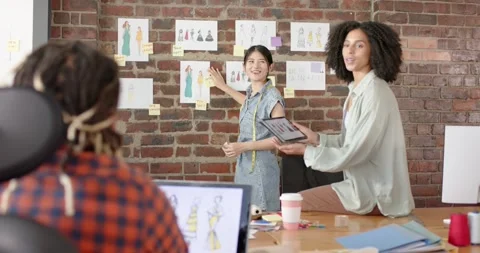 Busy diverse designers using tablet and discussing work in fashion design studio Stock Footage 340256497
