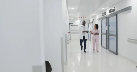 Busy diverse doctors using tablet and talking in hospital in slow motion Stock Footage 335807888