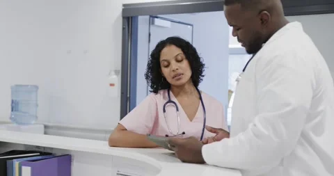 Busy diverse doctors using tablet and talking in hospital in slow motion Video stock 342798595