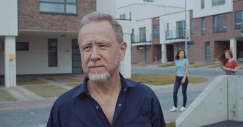 Busy elder man using smartphone outdoor asking for help of pretty young girls Stock Photos