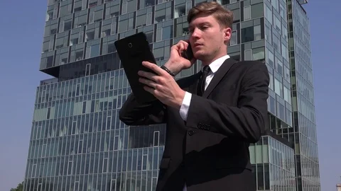 Busy engaged one businessman outdoor working on tablet discussing on cell phone Stock Footage