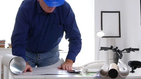 Busy Engineer in Office Open a Plan on the Table and Study Technical Details Stock Footage 102574174