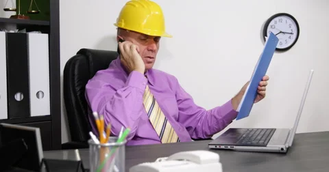 Busy Engineer Working on Laptop Read from Clipboard Talk to Mobile and Landline Stock Footage 68417401