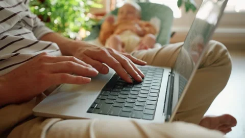Busy father working remotely on laptop computer, multitasking by babysitting Video stock 344279824