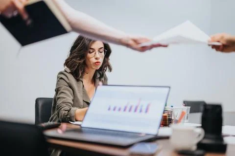 Busy female professional multitasking at work with multiple documents and laptop Foto stock