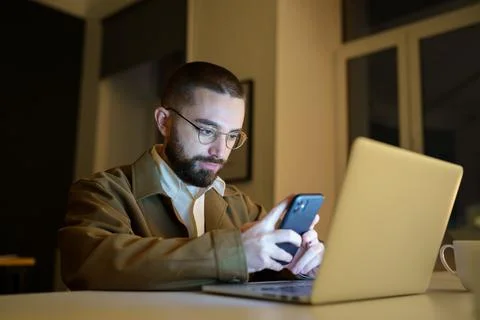 Busy front end developer or qa engineer testing app on smartphone work overtime Stock Photos
