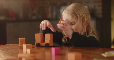 Busy game on the table performed by cute baby girl, orange wooden toy blocks Stock Footage 243217525