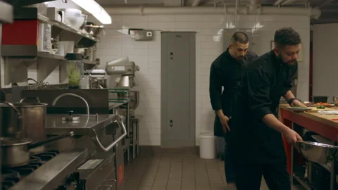 Busy group of professional chefs working at their stations at a long counter in Video stock 199459619