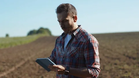 Busy handsome farmer agronomist using mobile technologies studying farm field Stock Footage 110953734