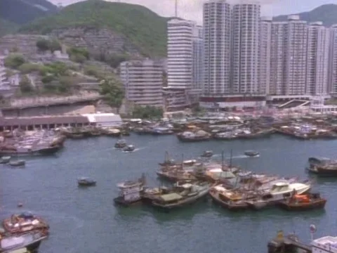 Busy harbor and settlements with green mountains in the background Stock Footage