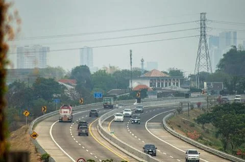 A busy highway with multiple vehicles, surrounded by greenery and urban bui.. Stock Photos