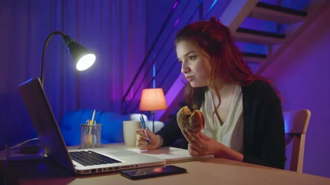 Busy Hungry Freelancer Girl Eats a Donut Junk Food, While Doing Her Online Job Stock Footage 182744602