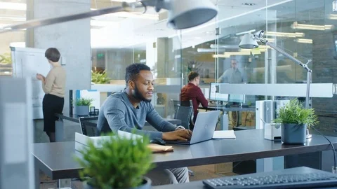 Busy International Office, African-American Man Working at His Desk on a Laptop. Stock Footage