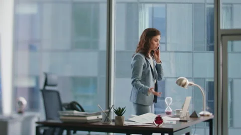 Busy lady talking mobile phone standing at office window. Woman complaining Stock Footage 252767752
