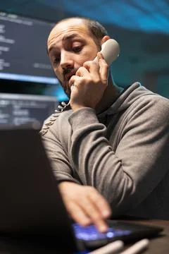 Busy Male Programmer Handling Client Call During Late Shift 스톡 사진