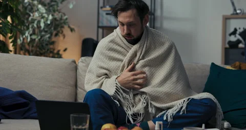Busy man with beard is sitting on sofa. He works on laptop, types on keyboard Stock Footage 218328992