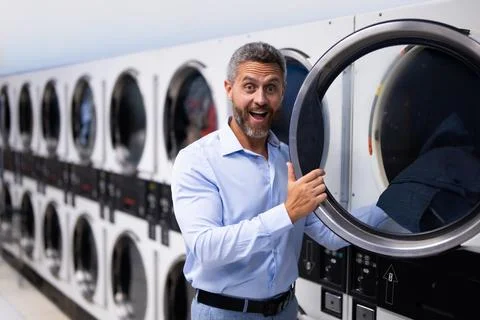 Busy man doing laundry and working on laptop. Stressed employee multitasking Stock Photos