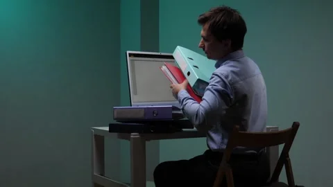 Busy man struggling with a stack of folders while working at a computer Stock Footage 345530424