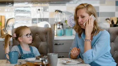 Busy mom talk discuss work job while her daughter is sitting at table on kitchen Stock Footage 135808649