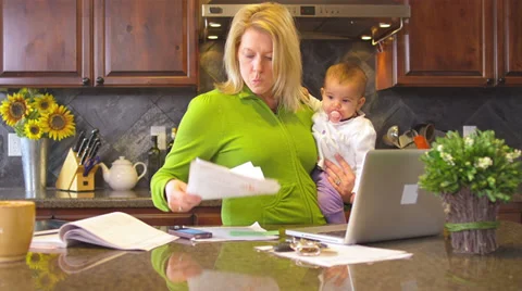 A busy mom tries to multitask with a baby in her arms Stock Footage