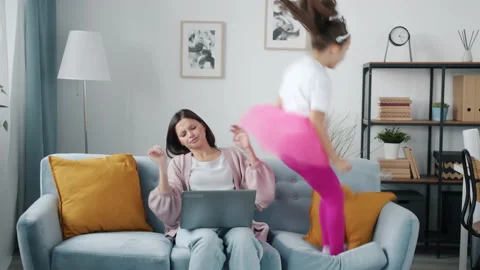 Busy mother working from home using laptop while annoying kid jumping and Stock Footage 163259597