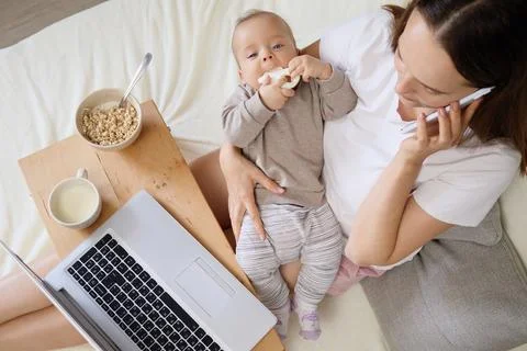 Busy multitasking mother working on computer talking on mobile phone and look Stock Photos