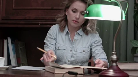 Busy student in glasses working on her report at the desk with a green lamp Vídeos de archivo 71059085