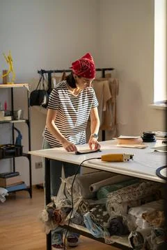 Busy tailor at work in studio. Female clothes designer cut fabric for sewing Stock Photos