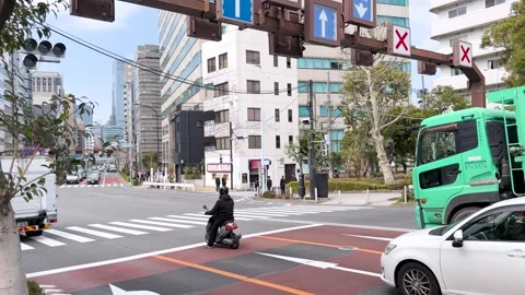 Busy Tokyo Street Intersection with Delivery Trucks and Motorcyclist Stock Footage 335923927