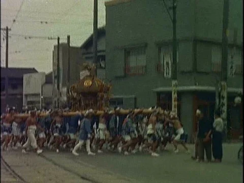 Busy Tokyo streets include a parade with men and women in Shinto costumes 스톡 동영상 75189384
