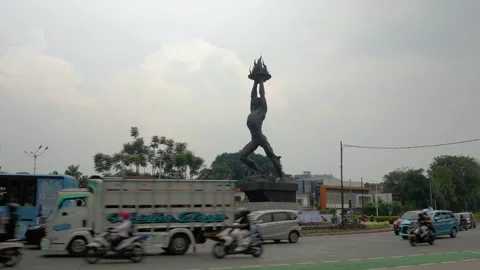 Busy traffic passing by Senayan roundabout stands the Statue of Youth Building Stock Footage 313150432