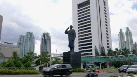 Busy traffic passing by Sudirman statue on Sudirman street in Jakarta Stock Footage 238072828