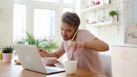 Busy young man having breakfast and using his laptop and smartphone Stock Footage 119137645