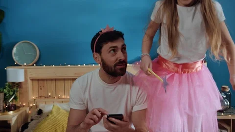 Busy young tired father wearing crown browsing on smartphone smiling to his Stock Footage 112261453
