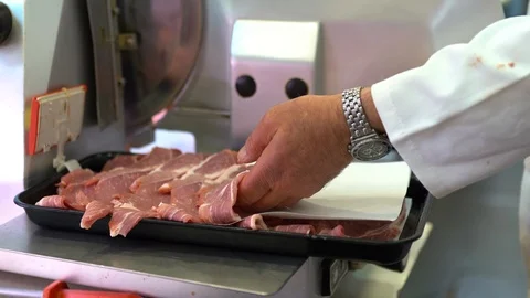 Butcher in apron cutting raw steaks on slicer machine. High quality meat Stock-Footage 111133787