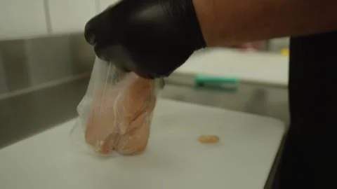 Butcher Bagging a Raw Chicken Breast on a White Cutting Board Vídeos de archivo 340300240