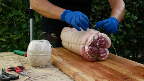 Butcher binds meat rolled up for pochette roast pork 스톡 동영상 242080194