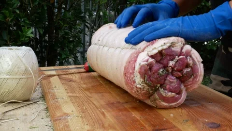 Butcher binds meat rolled up for pochette roast pork Stockbeeldmateriaal 242080551