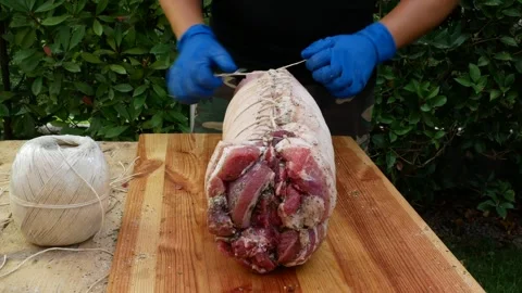 Butcher binds meat rolled up for pochette roast pork Stockbeeldmateriaal 242080640