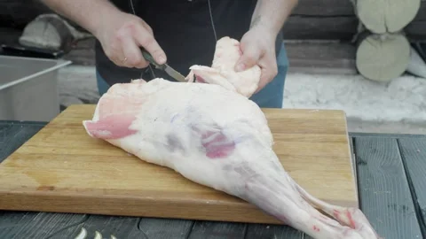 Butcher cuts piece of fat with layer of meat from leg of ram Stock Footage 248044685