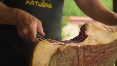 A butcher cuts a piece of ham to be enjoyed at a typical inn, in Bosnia Stock Footage 243836950