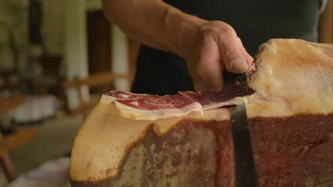 A butcher cuts a piece of ham to be enjoyed at a typical inn, in Bosnia Stock Footage 243838349