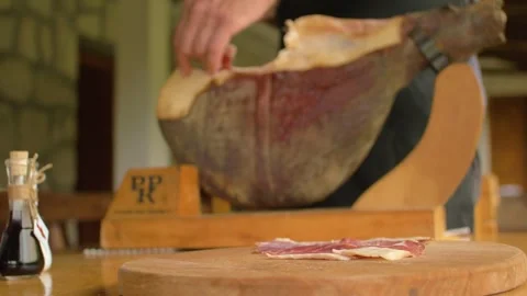 A butcher cuts a piece of ham to be enjoyed at a typical inn, in Bosnia Stock Footage 243840031