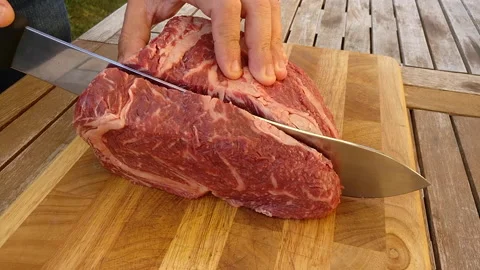 Butcher cuts slice of ribeye steak Stockbeeldmateriaal 238485686