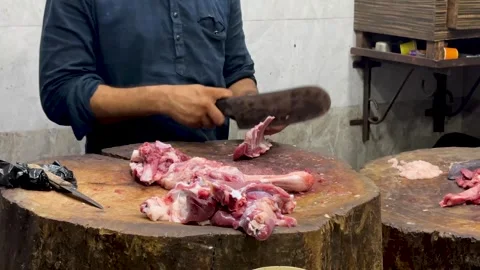 Butcher expertly chopping fresh mutton meat on a rustic wooden log Stock Footage 336942699