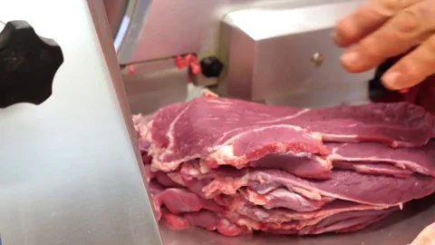 Butcher hand cutting raw meat on slicer machine Stock Footage 85314944
