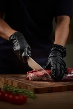 Butcher hands cutting raw beef steak on board Stock Photos