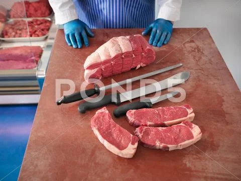 Butcher With Knives And Cuts Of Pork