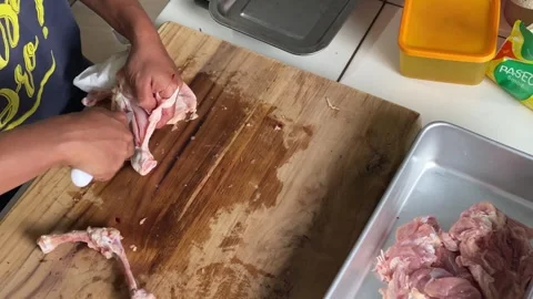 A butcher is processing a chicken thigh into fillets Stockbeeldmateriaal 347542029