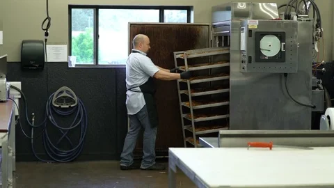 Butcher pulling racks of fish out of a commercial smoker Stock Footage 83464220